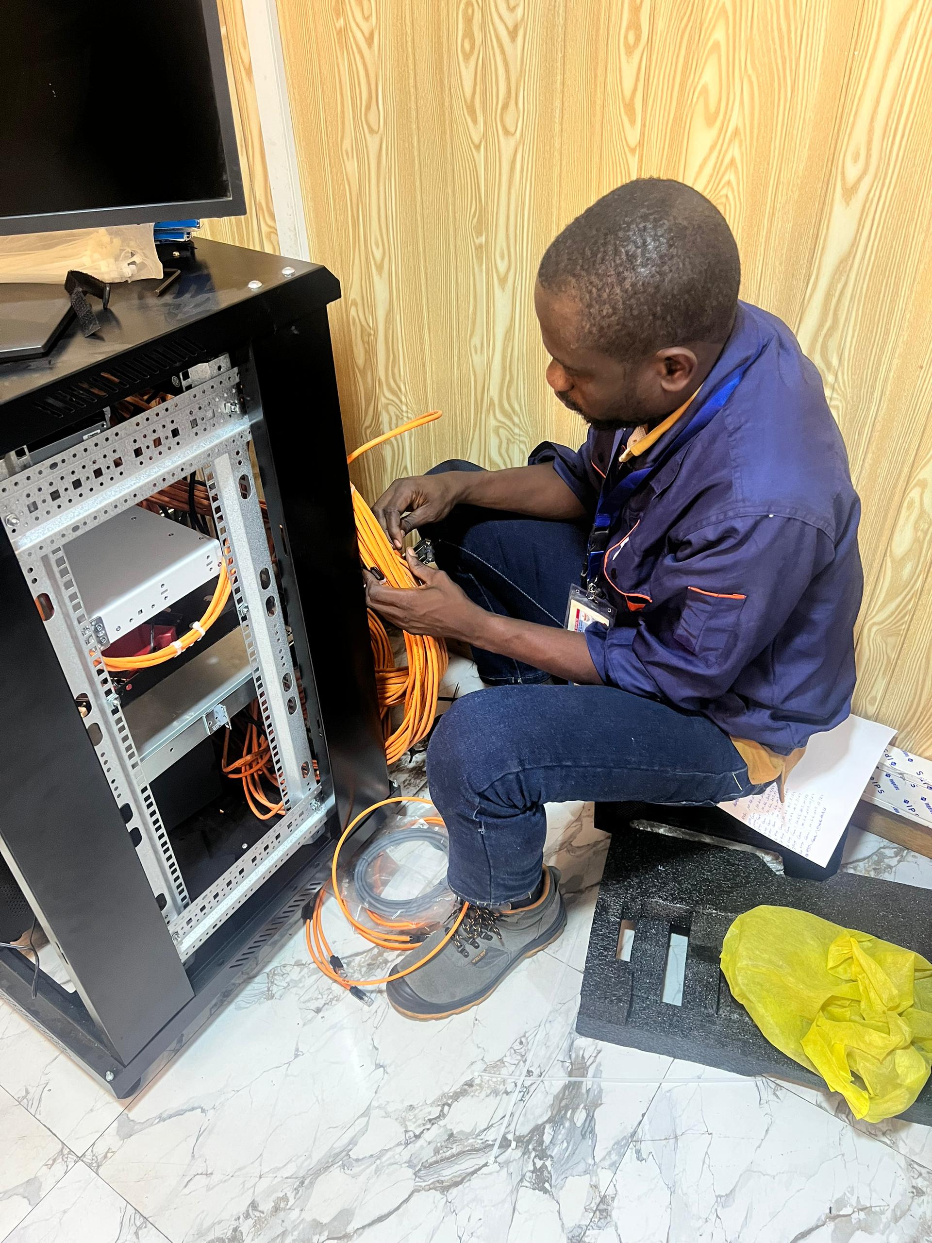 Travaux de câblage et de terminaison en fibre optique dans une baie réseau.