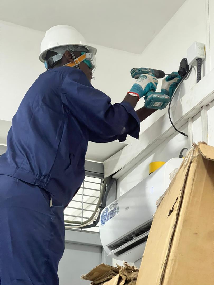 Technicien installant et fixant des équipements techniques sur site.